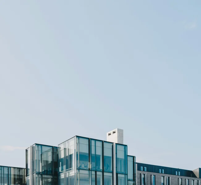 Moderne Gebäudefassade mit Glaselementen vor blauem Himmel